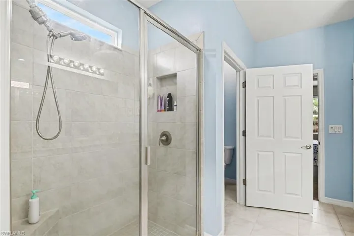 Bathroom with healthy amount of natural light, a shower stall, and light tile patterned floors