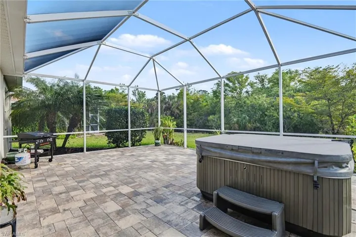 View of patio / terrace featuring a hot tub, area for grilling, a sunroom, and glass enclosure