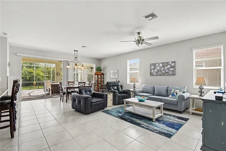 Living area with a ceiling fan, light tile patterned flooring, hanging lights, and healthy amount of natural light