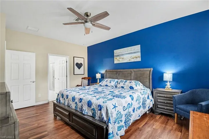 Bedroom with dark wood finished floors, ceiling fan, and connected bathroom