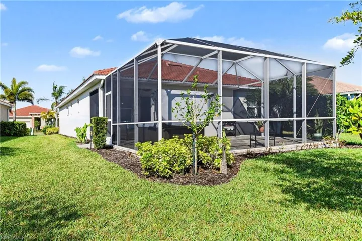 Rear view of property with a lanai, a sunroom, and a lawn