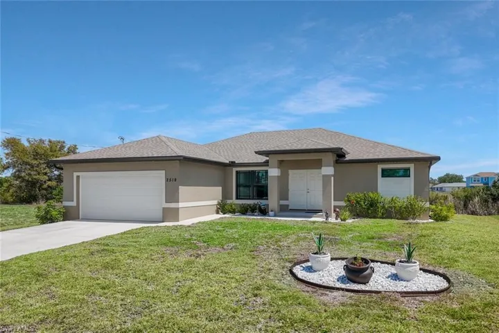 Prairie-style home featuring an attached garage, a front yard, stucco siding, and driveway