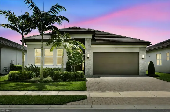 View of front of property with a tiled roof, decorative driveway, stucco siding, and an attached garage
