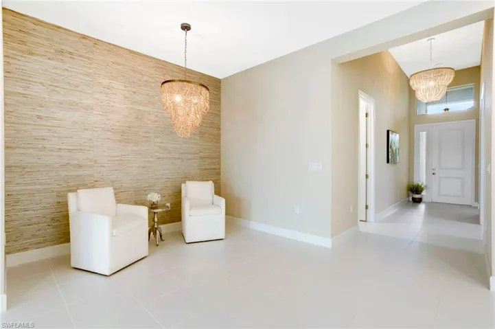 Unfurnished room featuring tile patterned floors, a notable chandelier, and an accent wall