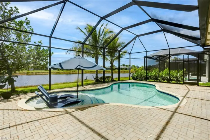 Outdoor pool featuring a lanai, a water view, and a patio