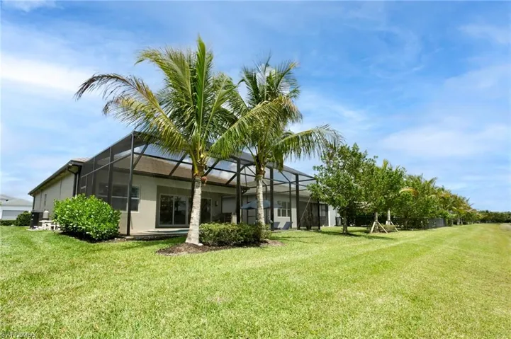 Rear view of property with stucco siding, a yard, and glass enclosure
