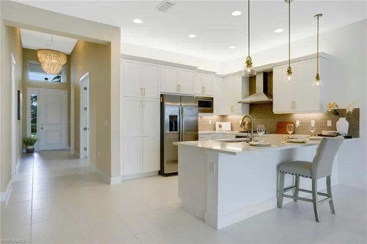 Kitchen featuring wall chimney range hood, a sink, appliances with stainless steel finishes, and backsplash