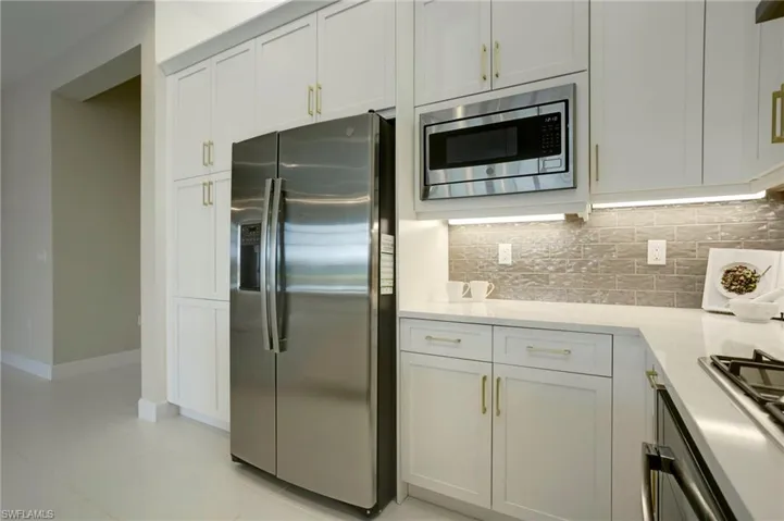 Kitchen with decorative backsplash, light countertops, stainless steel appliances, and white cabinets
