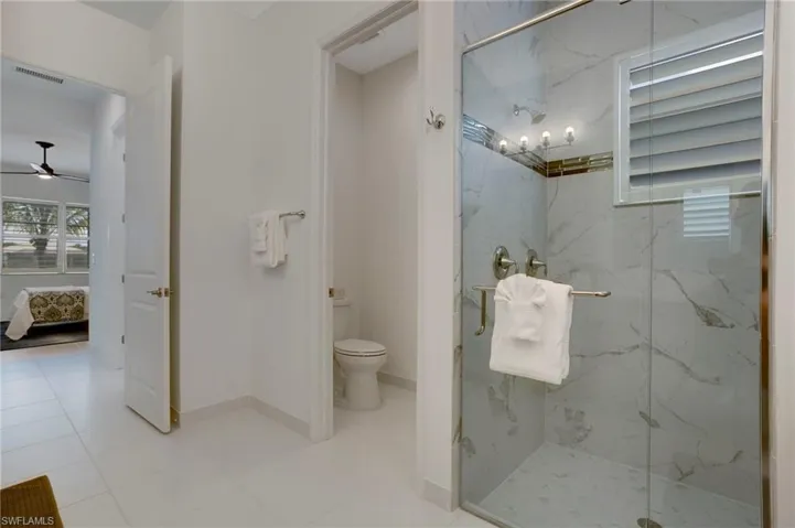 Ensuite bathroom with connected bathroom, toilet, a marble finish shower, and visible vents