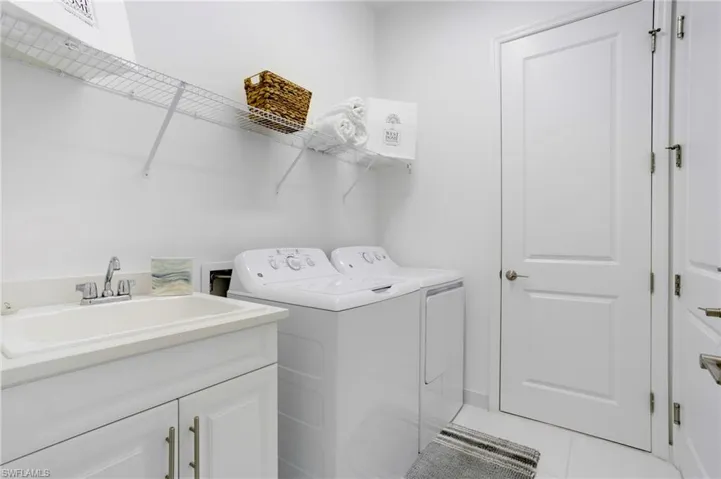 Laundry area with light tile patterned floors, a sink, and washer and clothes dryer