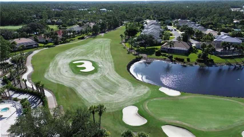 Aerial view of property and surrounding area featuring a golf course and nearby suburban area