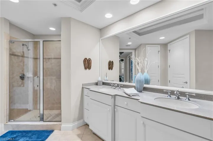 Main bathroom with large walk in shower, double vanity, crown molding, and tile floors