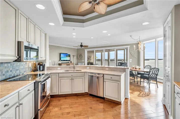 Kitchen featuring updated backsplash, kitchen peninsula, stainless steel appliances and light wood-type flooring