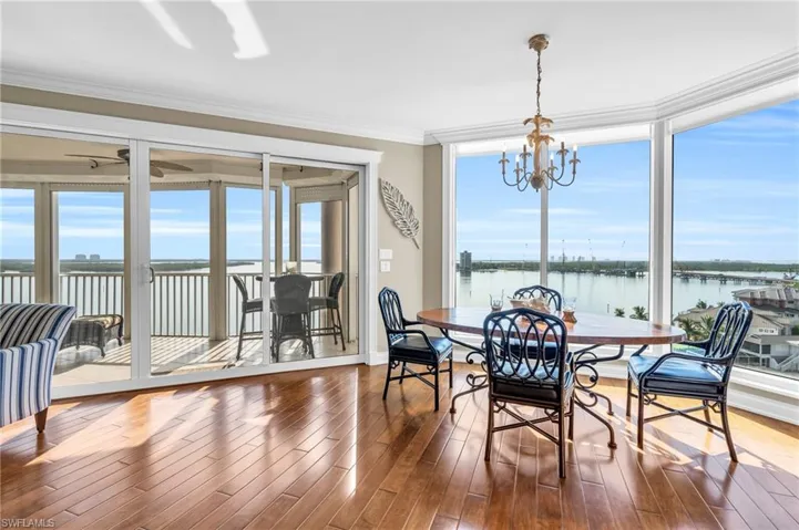 Dining room with crown molding, ceiling fan with notable chandelier, dark hardwood / wood-style floors, and a water view