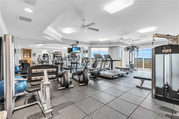 Gym with ornamental molding and ceiling fan
