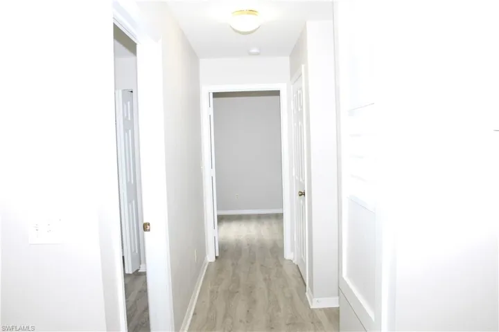 Hallway with light wood-type flooring and baseboards