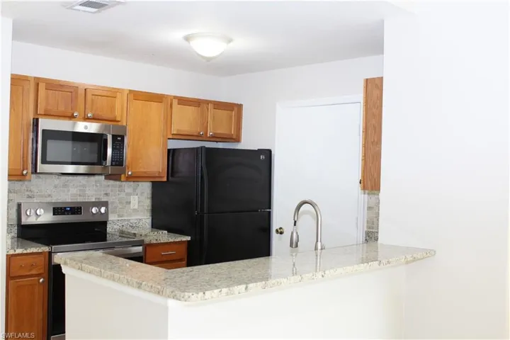 Kitchen with appliances with stainless steel finishes, decorative backsplash, kitchen peninsula, and sink