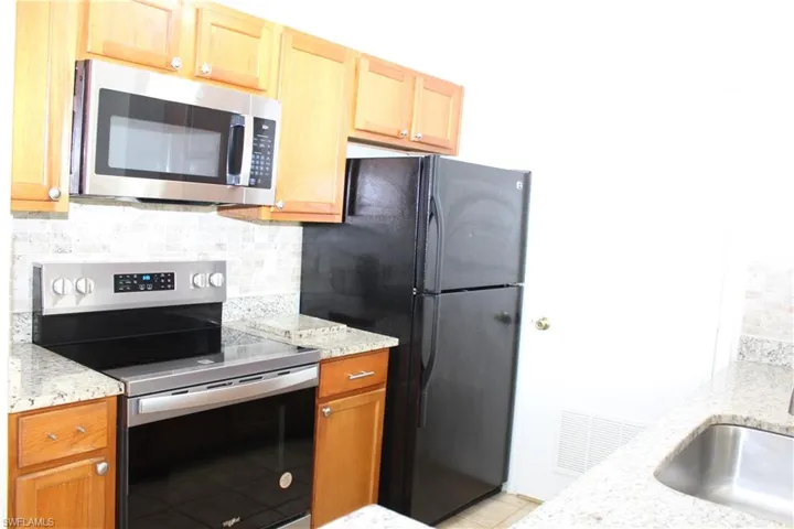 Kitchen featuring tasteful backsplash, sink, light stone counters, and stainless steel appliances