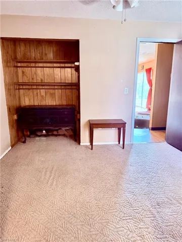 Unfurnished room with a textured ceiling, a ceiling fan, and carpet floors