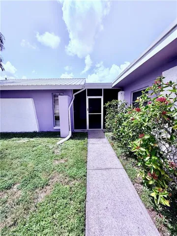 Entrance to property featuring stucco siding, a lawn, and a metal roof