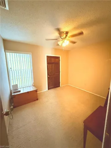 Spare room featuring a textured ceiling, a ceiling fan, and carpet floors