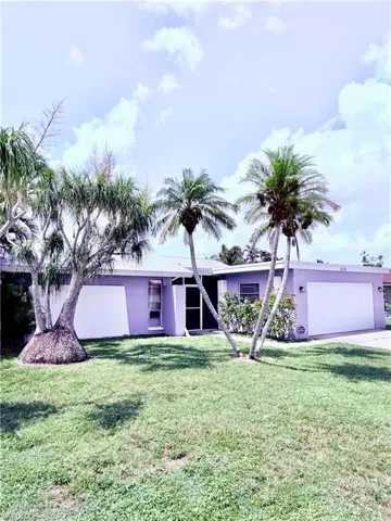 View of front of house featuring an attached garage, stucco siding, concrete driveway, and a front yard