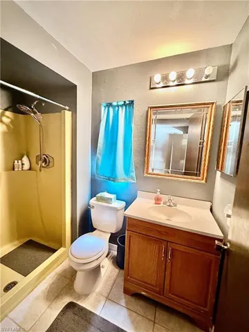 Full bathroom with a stall shower, vanity, tile patterned floors, and a textured wall