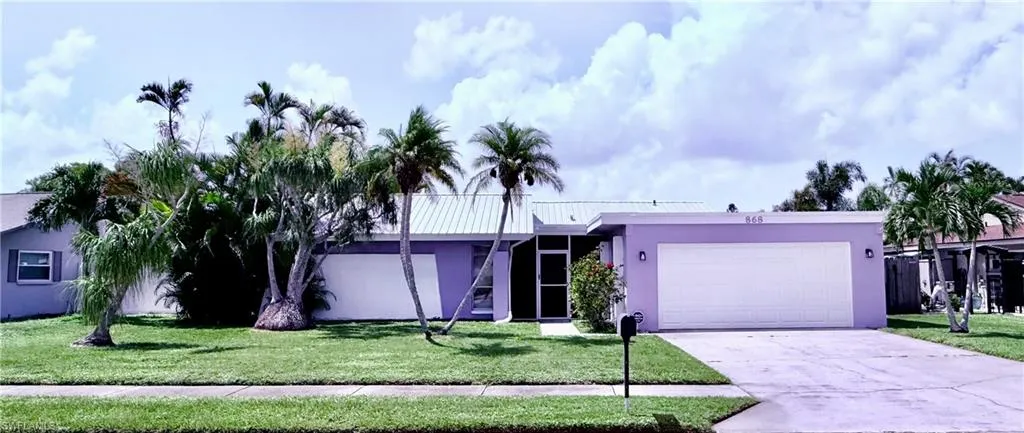 View of front of property with stucco siding, driveway, an attached garage, and a front lawn
