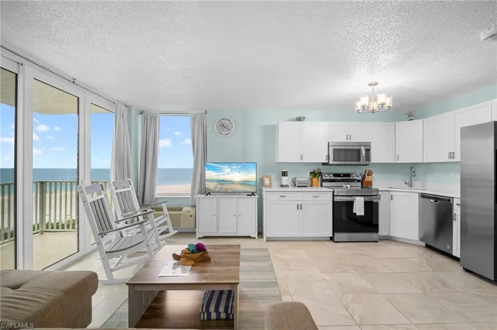 Kitchen featuring light countertops, stainless steel appliances, white cabinets, a textured ceiling, and a wall of windows