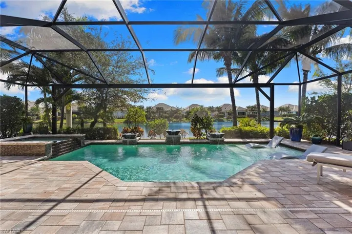 Combined pool / hot tub with a patio area, glass enclosure, a sunroom, and a water view