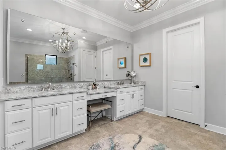 Bathroom with suspended lighting, a tile shower, vanity, and ornamental molding