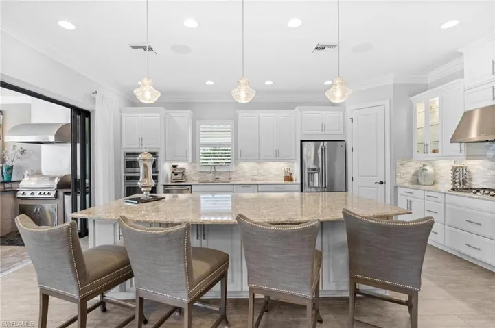 Kitchen featuring ornamental molding, pendant lighting, white cabinetry, and a kitchen breakfast bar