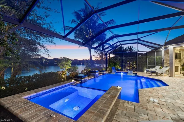 Integrated pool / spa with glass enclosure, a patio, a sunroom, and a water view