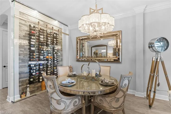 Dining area with ornamental molding, hanging lights, and light wood-style floors