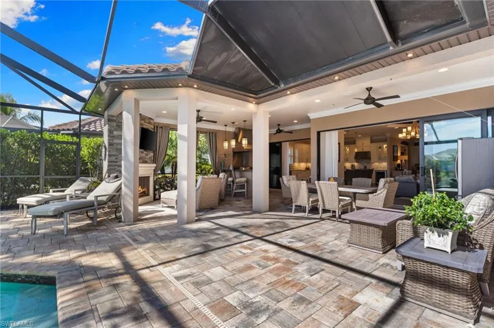 View of patio with a warm lit fireplace, a sunroom, glass enclosure, an outdoor living / dining area, and ceiling fan