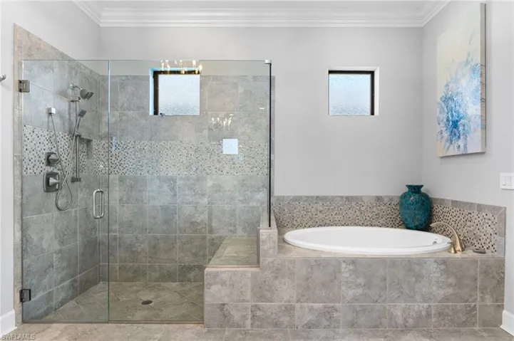 Bathroom featuring a stall shower, crown molding, and a garden tub