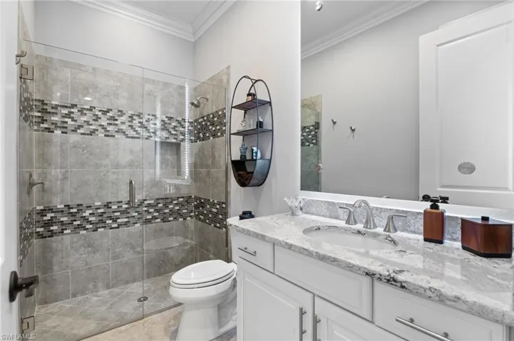 Bathroom with vanity, a shower stall, and crown molding