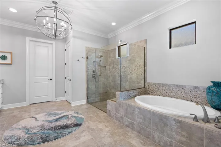 Bathroom with a bath, a shower stall, ornamental molding, suspended lighting, and tile patterned floors