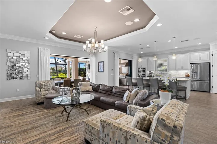 Living room featuring ornamental molding, a raised ceiling, and a chandelier
