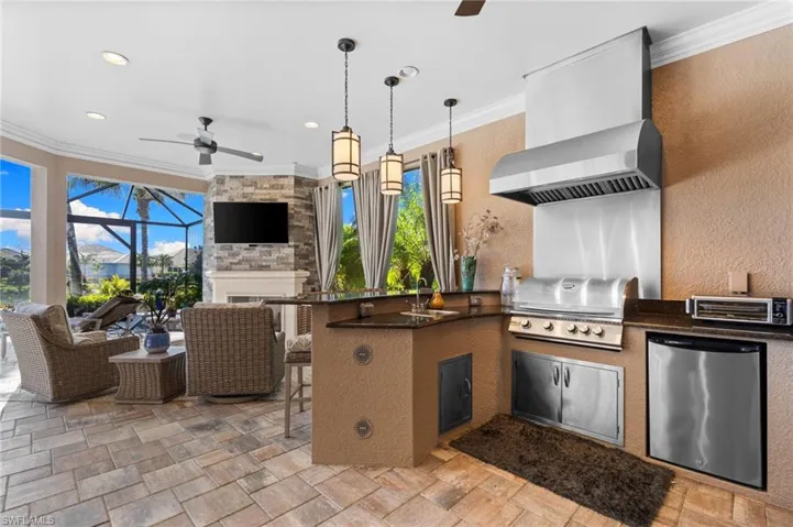 View of patio featuring glass enclosure, a ceiling fan, an outdoor kitchen, an outdoor lounge area with bar, and a sunroom