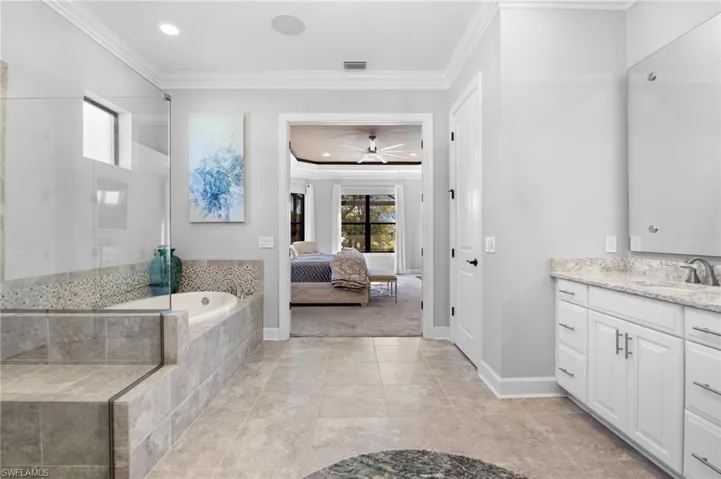 Ensuite bathroom featuring a stall shower, crown molding, vanity, a garden tub, and ceiling fan