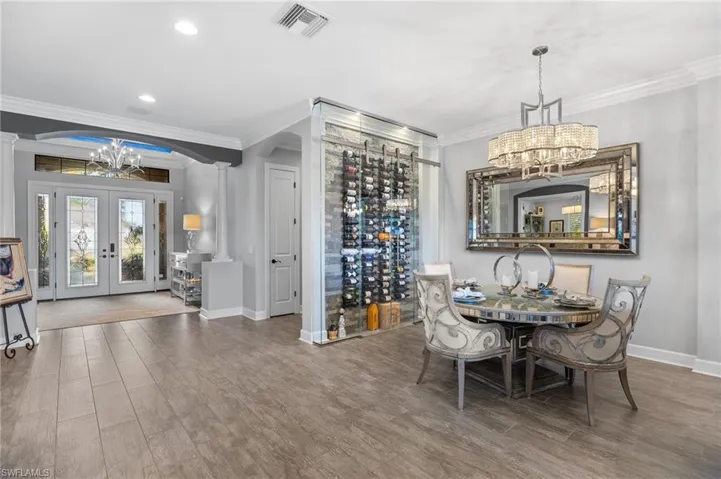 Dining area with a chandelier, french doors, ornamental molding, arched walkways, and wood finished floors