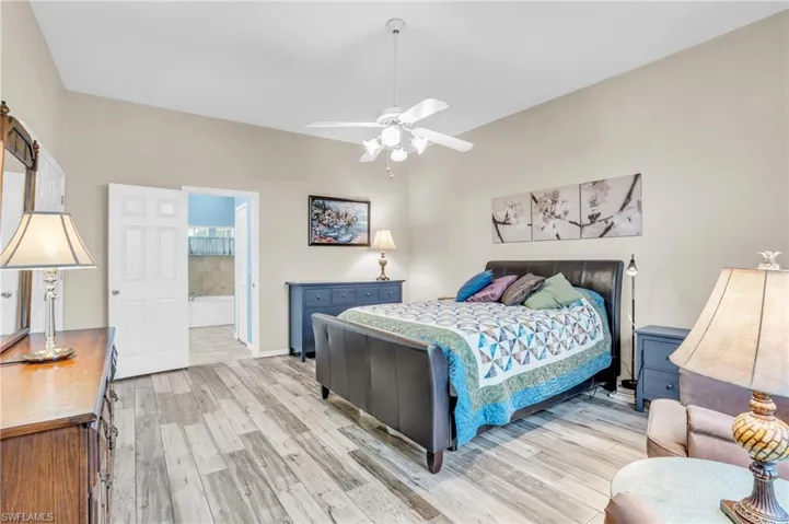 Bedroom with light hardwood / wood-style floors, connected bathroom, and ceiling fan