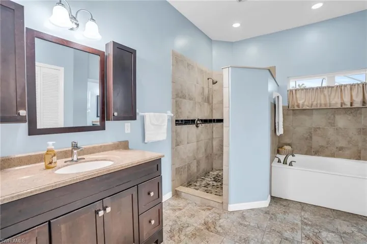 Bathroom featuring vanity, tile patterned floors, and shower with separate bathtub