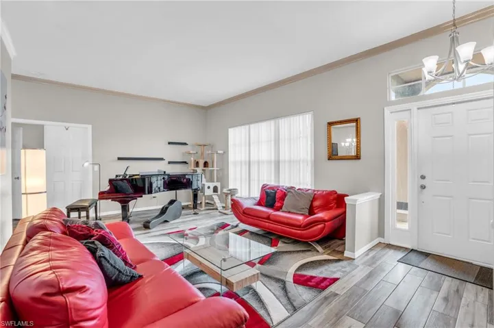 Living room with an inviting chandelier, hardwood / wood-style flooring, and ornamental molding