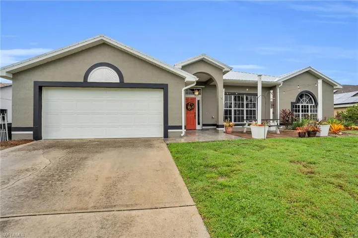 Ranch-style house with a garage, a front lawn, and solar panels