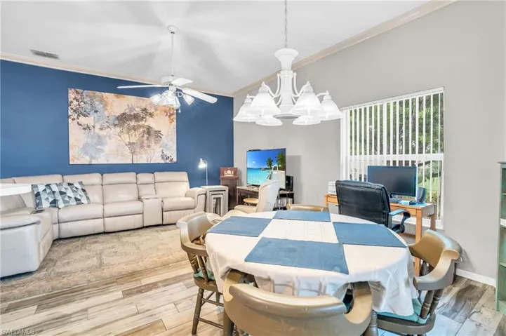 Dining room with wood-type flooring, crown molding, and ceiling fan with notable chandelier