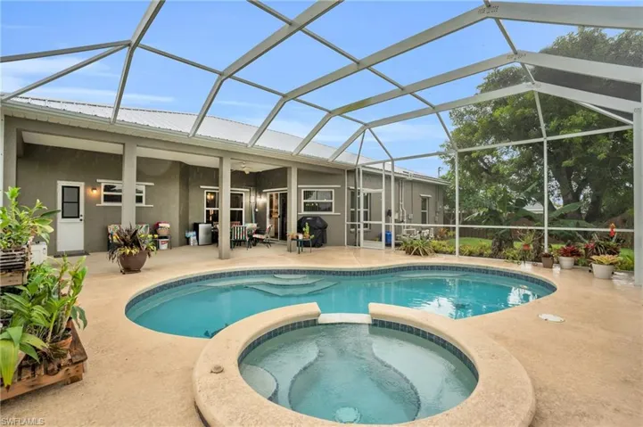 View of swimming pool with a patio, an in ground hot tub, and glass enclosure