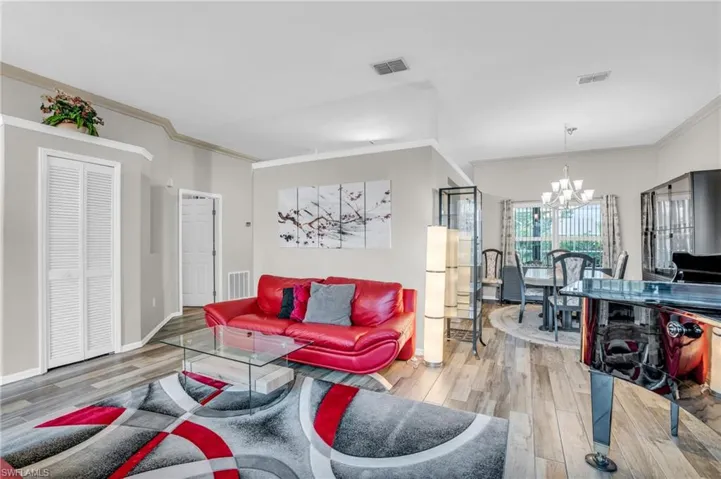 Living room featuring an inviting chandelier, ornamental molding, and hardwood / wood-style floors
