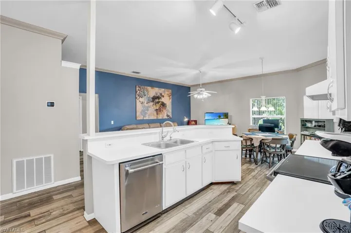 Kitchen featuring white cabinets, dishwasher, ceiling fan, and pendant lighting